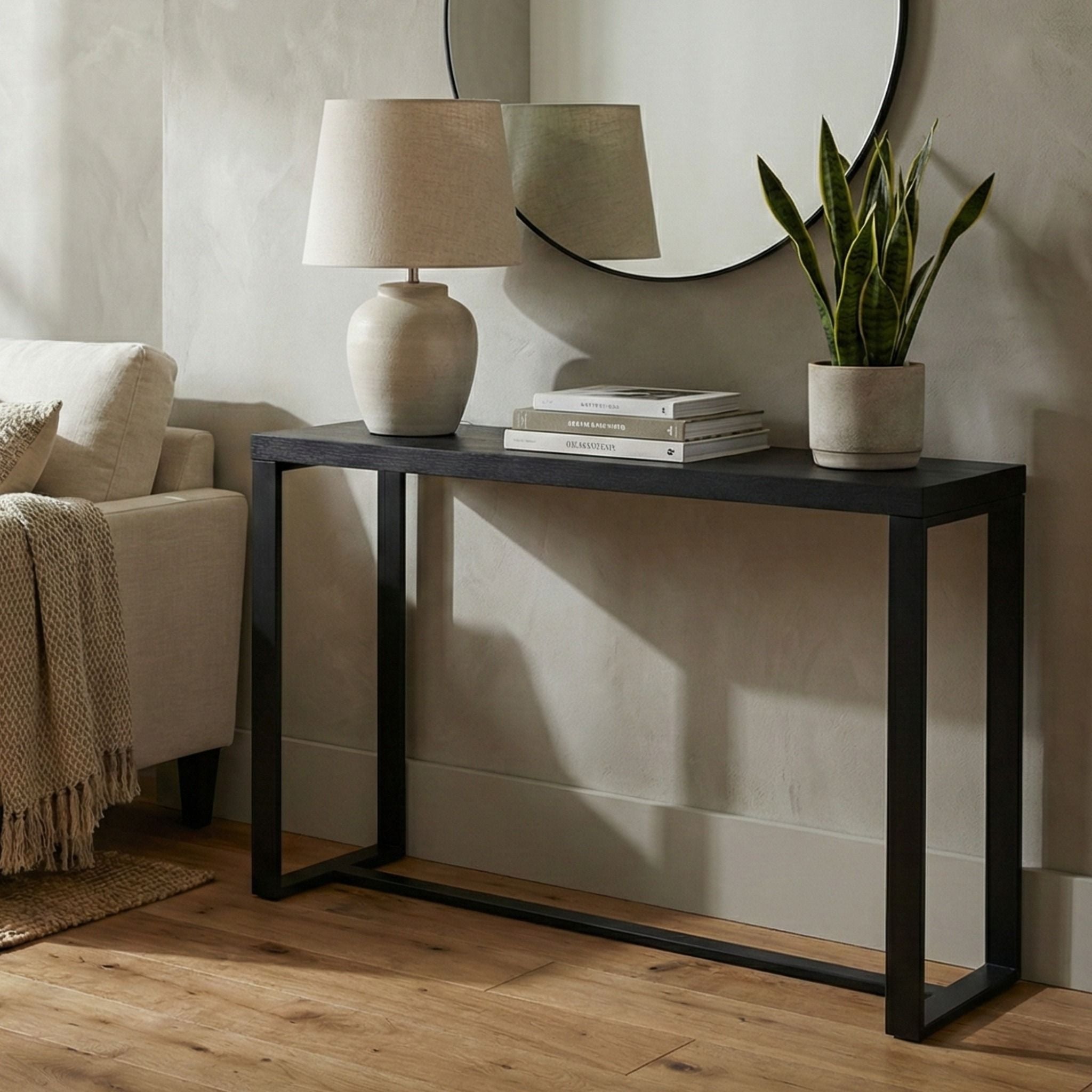 Black console table styled in a modern living room with lamp, books, and plant, perfect as an entryway or sofa table.